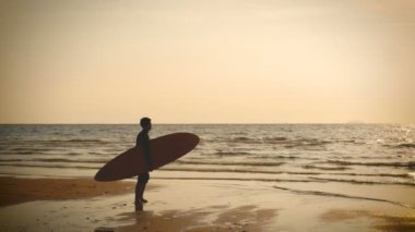 4k. tropikal plajda günbatımı uzun sörf panoları ile deniz plajında sörfçü adam stand Silhouette, Vintage renk tarzı 