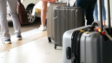 Havaalanı varış terminalinde taksi otoparkında taksi kuyruğu beklerken hatta duran büyük silindir bagajlı yolcunun 4k görüntüleri