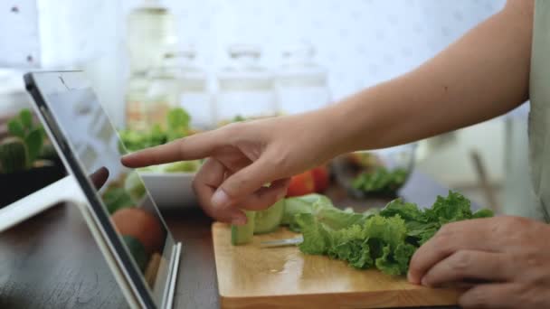 女性の手スライス緑の野菜は タブレットを介してウェブサイト上のオンラインビデオクリップを調理する調理のための食材を準備します 現代のライフスタイルコンセプトのためのインターネット技術上の料理コンテンツ — ストック動画