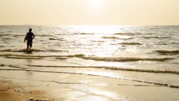 熱帯のビーチで日没時に長いサーフボードで実行している若い幸せなサーフマンのシルエット 日光フレアと美しい光と日没時に海岸のビーチでサーファー — ストック動画