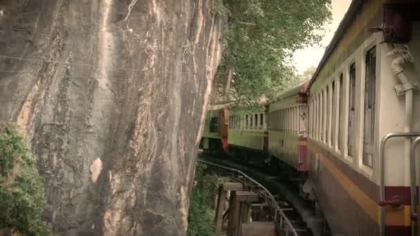 4K镜头的古代列车运行在锋利的弧形铁轨弯曲到横跨桂河的一座桥上 电影彩色滤光片效果 外国游客在泰国的热门景点 — 图库视频影像