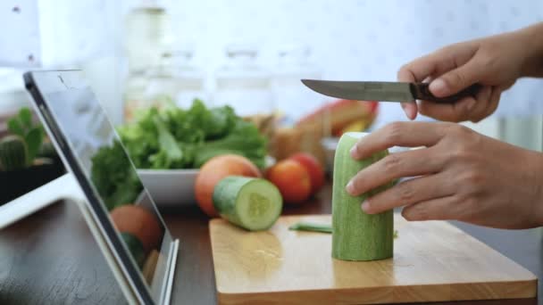 女性手切片黄瓜 准备烹饪原料跟随烹饪在线视频剪辑在网站上通过平板电脑 现代生活方式概念互联网技术的烹饪内容 — 图库视频影像