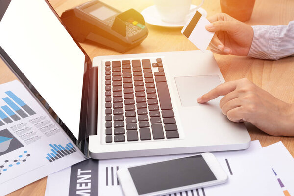 woman holding a credit card and purchase making online payment via  computer notebook laptop with blank white screen in workplace