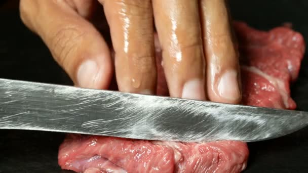 4K映像 まな板に鋭いナイフでシェフの手のスライス生牛肉をクローズアップ — ストック動画