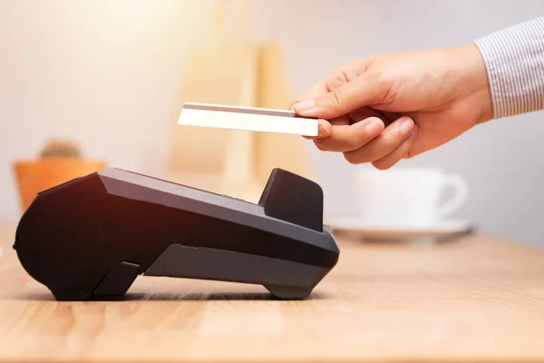 hand of customer using credit cart for payment at point of sale terminal in shop during shopping time, cashless technology and credit card payment concept