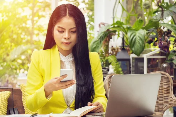 Portret van mooie en zelfverzekerde Aziatische zakenvrouw zittend in de voorkant van laptop laptop en controleren op telefoon voor update afspraak op de werkplek. — Stockfoto