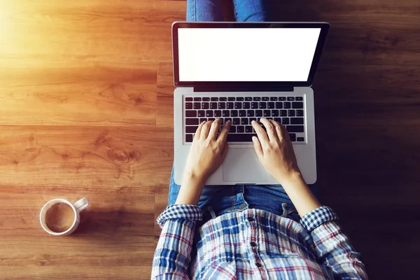 top view of people typing on laptop computer with blank white screen from home on wooden floor with copy space