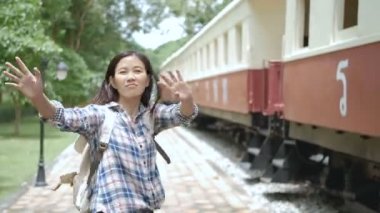 4k. Asya turist kadın el sallayarak tren istasyonunda tren bırakarak departe elveda demek. Hoşça kal