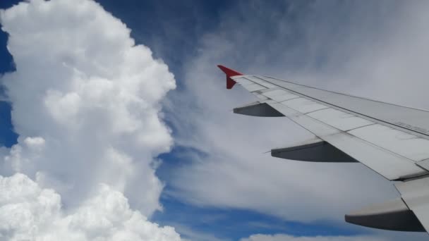 4K映像飛行機着陸飛行 白い雲と青い空の上を飛ぶ飛行機の翼 航空機による移動時間の窓面からの美しい航空写真 休暇時間 — ストック動画