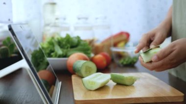 4k. Bayan el salatalık kabuğu dilimleme, pişirme için malzemeler hazırlamak pişirme online video klip Web sitesinde tablet üzerinden izleyin. modern yaşam tarzı konsepti için internet teknolojisindeki içerik pişirme