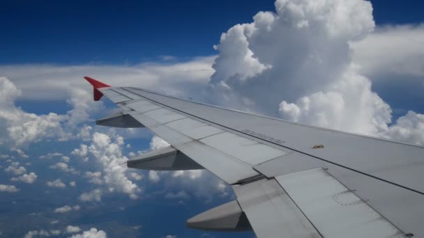 4K映像飛行機着陸飛行 白い雲と青い空の上を飛ぶ飛行機の翼 航空機による移動時間の窓面からの美しい航空写真 休暇時間 — ストック動画