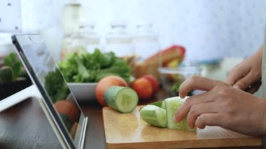 4k. kadın el kesim ve dilim salatalık, pişirme için malzemeler hazırlamak pişirme online video klip Web sitesinde tablet üzerinden izleyin. modern yaşam tarzı konsepti için internet teknolojisindeki içerik pişirme