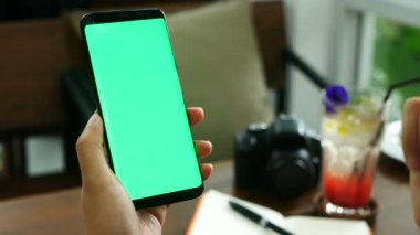 4k görüntüleri. Kadın el kahve dükkanında yeşil ekran, mobil içerik okumak için telefon ekranında parmağınızı slayt ile akıllı bilye tutarak yakın