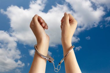 insan kaçakçılığı, köle işçilik ve işgücü baskı sorunları kavramı. iki el arka planda mavi gökyüzü ile kelepçeli hapsedildi