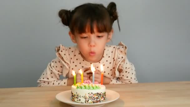 ケーキとスマイリーフェイスのかわいい女の子 家族と自宅で誕生日のお祝いパーティーのためのキャンドルを吹く — ストック動画