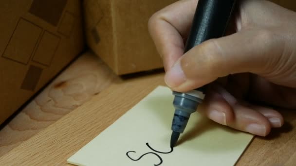 黒魔術ペンと配達箱に貼り付けメモ付きのメモ帳で販売された女性手書きの単語の4K映像 — ストック動画