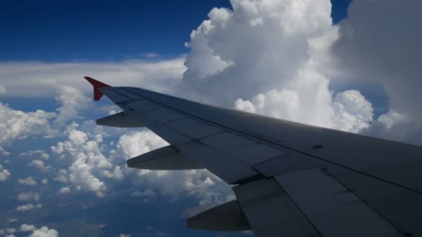 4K映像飛行機着陸飛行 白い雲と青い空に飛んでいく飛行機の翼 航空機による移動時間の窓面からの美しい航空写真 休暇時間 — ストック動画