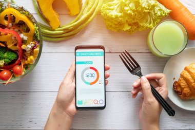 Kalori sayma, diyet, gıda kontrolü ve kilo kaybı kavramı. salata, meyve suyu, ekmek ve sebze ile yemek masasında onu akıllı telefon Kalori sayaç uygulaması kullanarak kadın