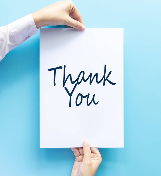 woman hand holding card with the word thank you isolated on blue background, studio shot