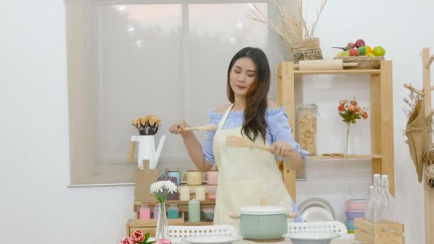 美丽的亚洲妇女拿着包在厨房跳舞 感觉享受烹饪后餐桌锅 菜和厨具与笑脸 — 图库视频影像