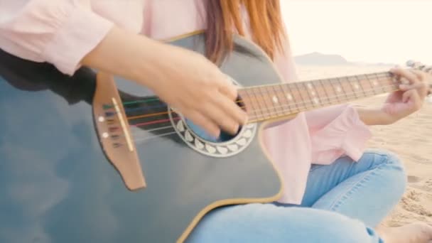 特写长发妇女玩原声吉他在沙滩上与柔和的风在日落时间 感觉放松 — 图库视频影像