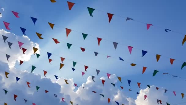 カラフルなデザインの装飾三角形のフェアフラグは 楽しいフェスティバルパーティーイベント 祝祭の休日 カーニバルフェスティバルイベントのために青空の背景にぶら下がって風に吹く — ストック動画