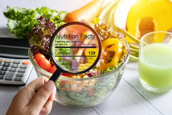 Ernährungsinformationskonzept. Verwenden Sie die Lupe, um die Details der Ernährungsfaktoren von Lebensmitteln, Salatschüsseln, heranzuzoomen — Stockfoto