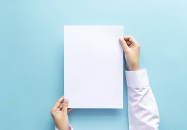 El afiş veya davetiye mavi arka planda izole kadar boş beyaz boş mektup kağıt boyutu A4 tutan ellerini yakın.