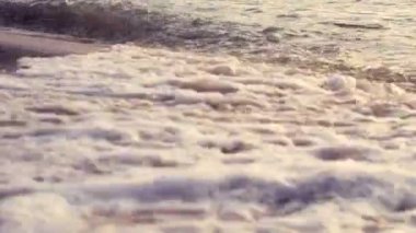 4K. close up of sea ripple waves washed on the beach at sunset time with selective focus dof and vintage style. sea beach background