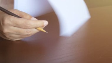 4 bin. Kadın kağıt üzerinde okuyor, sayfayı çeviriyor ve belgedeki metni işaretlemek için kalem kullanıyor