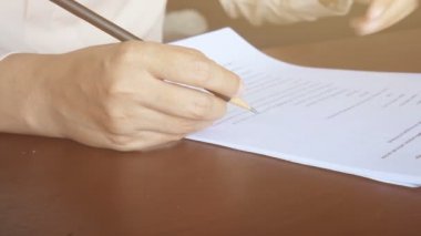 4 bin. Kadın kağıt üzerinde okuyor, sayfayı çeviriyor ve belgedeki metni işaretlemek için kalem kullanıyor