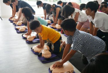 Bangkok, Tayland - 6 Ekim 2019: Çocuk ve yetişkinin bir parçası, Bangkok, Tayland 'da 6 Ekim 2019' da ana güvenli yaşam için manken göğsünün üzerindeki el pompasını kullanarak CPR İlk Yardım Eğitim kursuna katılıyor. 