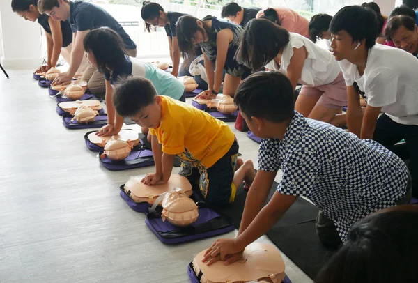 Bangkok, Tayland - 6 Ekim 2019: Çocuk ve yetişkinin bir parçası, Bangkok, Tayland 'da 6 Ekim 2019' da ana güvenli yaşam için manken göğsünün üzerindeki el pompasını kullanarak CPR İlk Yardım Eğitim kursuna katılıyor. 