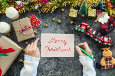 Noel sezonu boyunca tebrik kartına Mutlu Noeller ve hediye festivali. Masada Noel süsü olan süslemeler.