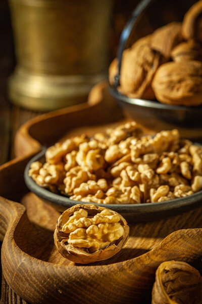 Walnuts, decorticated walnuts and walnut shells on wooden background