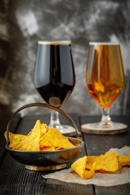 Tuzlu aperatifler, cips ve iki bardak koyu ve hafif bira. Boşluk yok. Boşluğu kopyala.