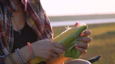 anne ve oğlu ızgarada mısır pişirir, piknikte, nehir kıyısında, gün batımında, kömürlerde mısır kavurma, 100fps