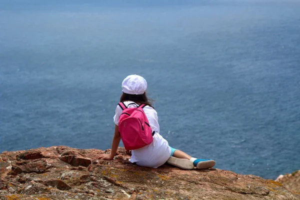Uçurumun kenarında oturma, deniz, Berlengas, Portekiz seyir sırt çantası ile çocuk