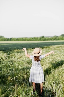 Şapkalı neşeli bir kız buğday tarlasında yürür. Sevinir ve dans eder.