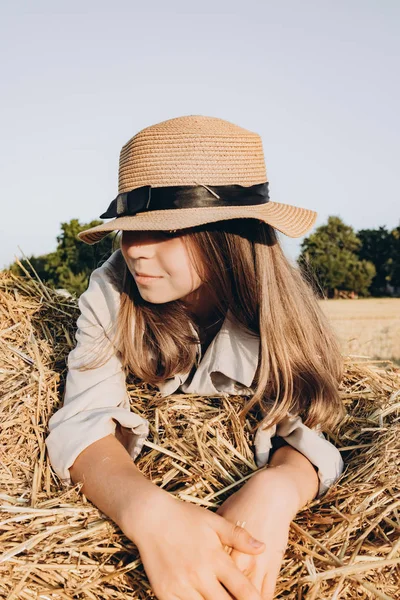 Niña con sombrero Al aire libre disfrutando de la naturaleza. Se encuentra en un pajar —  Fotos de Stock
