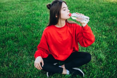 Atletik genç kız stadyumda egzersiz yapıyor. Eşofmanlı bir kız stadyumda spor yapıyor. Düzgün görünüyor ve gülümsüyor. Kız eğleniyor. Alıştırma yapmayı sever..