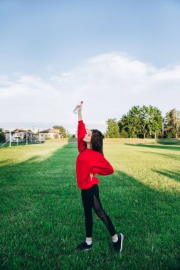 Atletik genç kız stadyumda egzersiz yapıyor. Eşofmanlı bir kız stadyumda spor yapıyor. Düzgün görünüyor ve gülümsüyor. Kız eğleniyor. Alıştırma yapmayı sever..