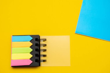 Sarı-mavi arka planda çok renkli sayfaları olan bir not defteri. Kırtasiye konsepti.