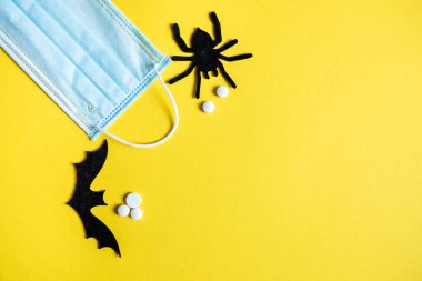 Sarı arka planda koruyucu maske ve Cadılar Bayramı yazıları. Cadılar Bayramı sembolü 2020