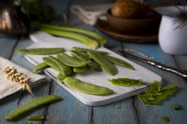 Mavi ahşap bir masada bezelye kabukları