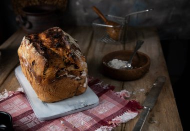 Tahta bir masada fındıklı taze pişmiş ekmek ve kurutulmuş kayısı.