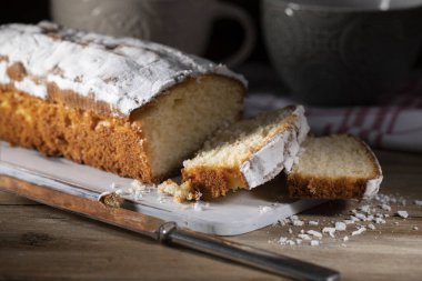 Tahta masada taze dilimlenmiş kek ve pudra şekeri.