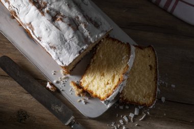 Tahta masada taze dilimlenmiş kek ve pudra şekeri.