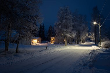 İsveç 'in kışlık bir köyünde elektrikli ışıklandırması olan bir akşam sokağı.