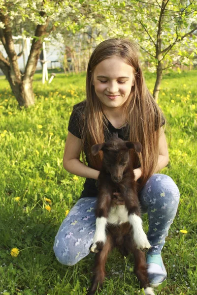 Дівчина і дитина козел в квітковому саду — стокове фото